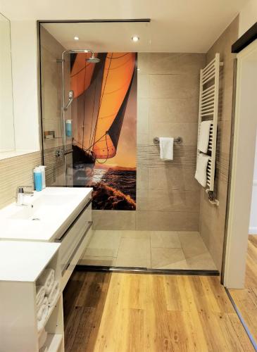 a bathroom with a shower with a sail painting on the wall at Victoria Suites in Bad Saarow