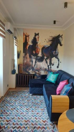 una sala de estar con sofá y una pintura de caballos en la pared en Luxury Stable 1 en Rēzekne