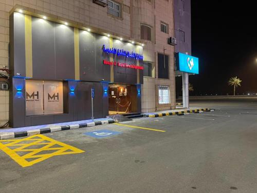 un estacionamiento frente a un edificio por la noche en منازل الشمال للشقق المخدومة Manazel Al Shamal Serviced Apartments, en Hail