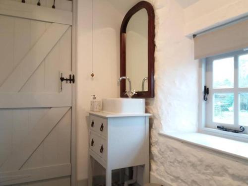 La salle de bains est pourvue d'un lavabo et d'un miroir à côté d'une porte. dans l'établissement The Bake House (Berryl Farm Cottages), à Whitwell