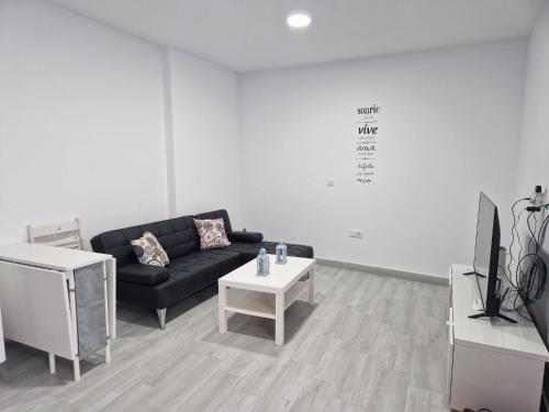 sala de estar con sofá negro y mesa en Apartamento mi currilla, en Sanlúcar de Barrameda