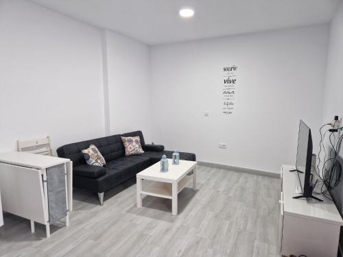 salon z czarną kanapą i stołem w obiekcie Apartamento mi currilla w mieście Sanlúcar de Barrameda