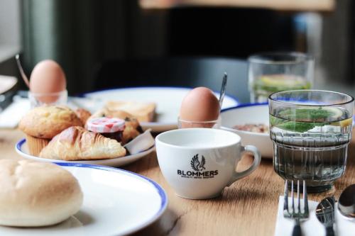 einen Tisch mit Teller mit Lebensmitteln und einer Tasse Wasser in der Unterkunft Boutique Hotel Jeroen in ’s-Hertogenbosch