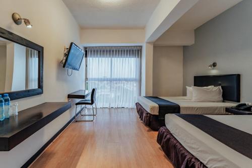 a hotel room with two beds and a flat screen tv at Hotel Maya Yucatan in Mérida