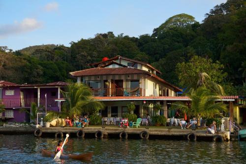 uma mulher num caiaque na água em frente a uma casa em Casa Congo - Rayo Verde - Restaurante em Portobelo