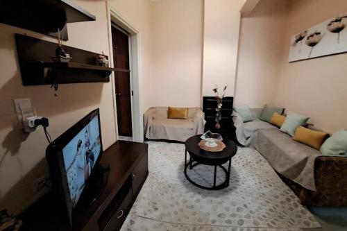 - un salon avec un canapé et une télévision dans l'établissement Υπεροχο διαμέρισμα ηλιουπολης, à Athènes