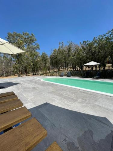 an empty swimming pool with benches and an umbrella at Casa Paraiso San Pablo in Oaxaca City