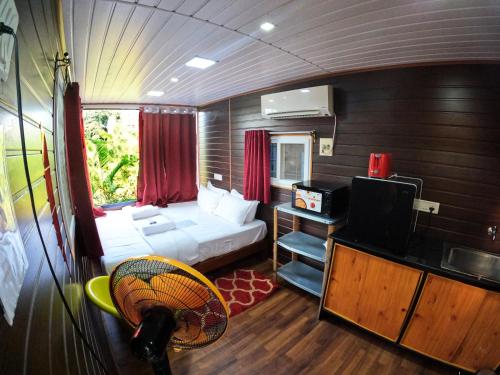 a small room with a bed and a tv in it at Wow Farm House & Resort near Pondicherry in Auroville