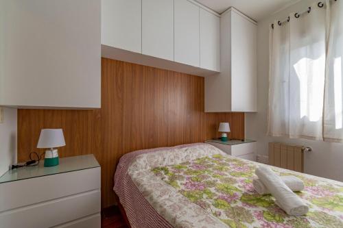 een slaapkamer met een bed, 2 lampen en een raam bij Rosa Edifício English Place in Gramado