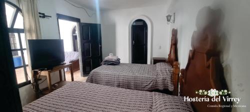 a bedroom with two beds and a tv in it at Hosteria Del Virrey - B&B in San Cristóbal de Las Casas