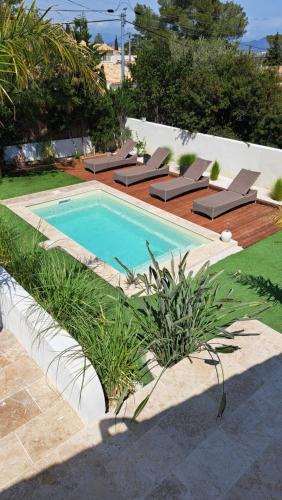 a swimming pool in a yard with lounge chairs next to it at Villa Junna in Fréjus
