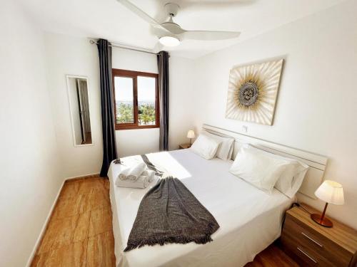 une chambre avec un lit blanc avec un ventilateur de plafond dans l'établissement Blue Ocean Holiday Home, à Playa del Ingles