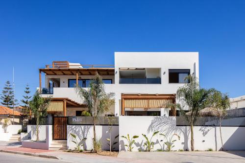 a white house with palm trees in front of it at Isla Luxury Apartment - Private Pool - 100m from the beach in Rethymno Town