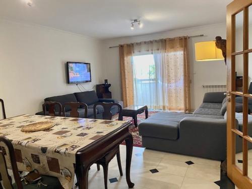 a living room with a couch and a table at Apartamento novo muito confortável com vista Rio in Algés