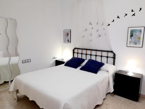 een slaapkamer met een bed met blauwe kussens en vogels aan de muur bij Mi rincón de Rota in Rota