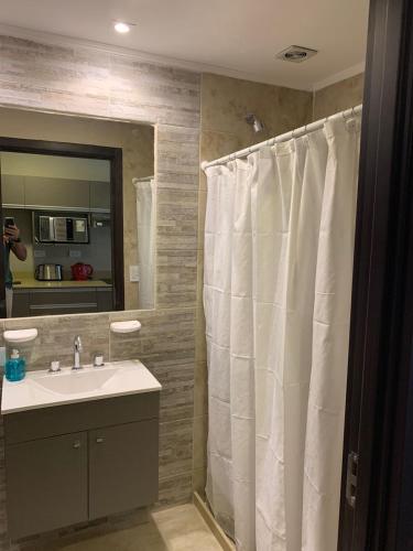 a bathroom with a white shower curtain and a sink at Apart Casa De Playa Premium in Necochea
