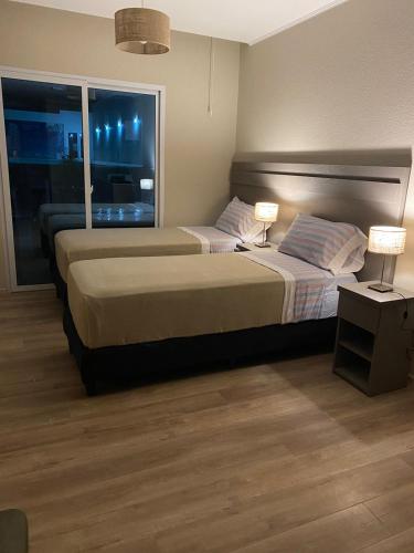 two beds in a hotel room with a window at Apart Casa De Playa Premium in Necochea