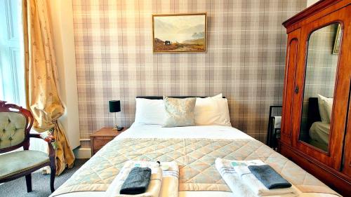 a bedroom with a bed and a chair and a mirror at Heatherlie House Hotel in Selkirk
