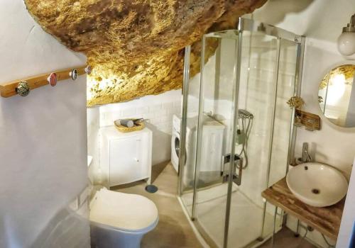 ein Bad mit einer Glasdusche und einem Waschbecken in der Unterkunft Casa Cueva La Luna in Setenil de las Bodegas