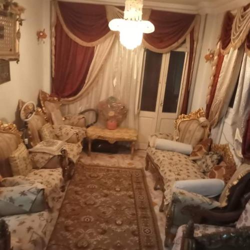 にあるمنزل مصطفى العوامのリビングルーム(ソファ、椅子、シャンデリア付)