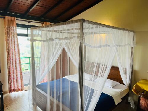 a bedroom with a canopy bed with a window at Ambiente Guest House in Ella