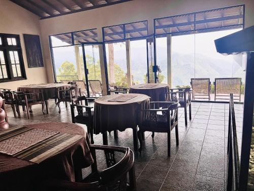 a restaurant with tables and chairs and a large window at Ambiente Guest House in Ella
