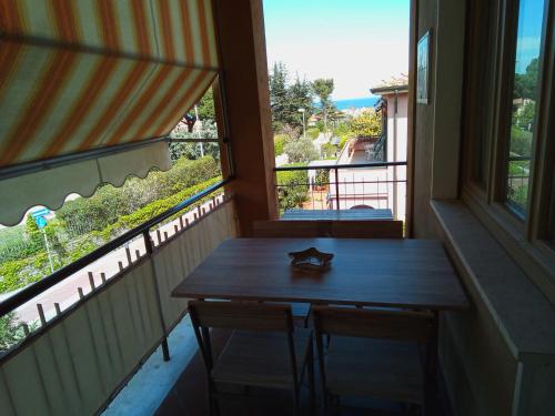 un balcone con tavolo in legno, 2 sedie e finestra di Appartamento Loretta a Marciana Marina