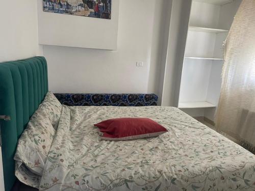 uma cama com uma almofada vermelha em cima em Appartement num3 Carthage byrsa em Douar ech Chott