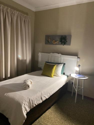 a bedroom with a bed with a yellow pillow and a table at Straebe Stay in Bloemfontein