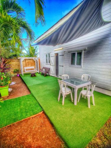 a patio with a table and chairs on the grass at Bungalow Bois Détente in Capesterre-Belle-Eau