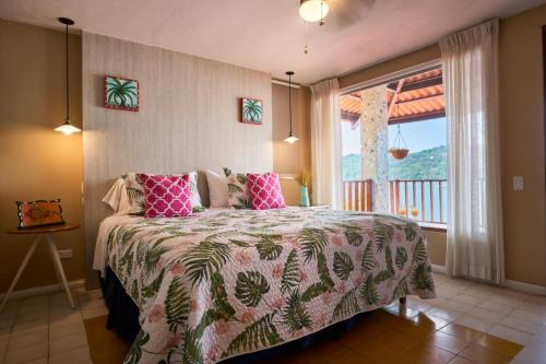 um quarto com uma cama com almofadas cor-de-rosa e uma janela em Casa Congo - Rayo Verde - Restaurante em Portobelo