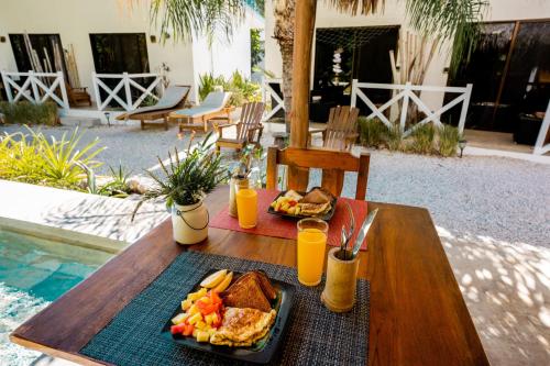 a table with breakfast foods and orange juice on it at Antema Lodge Secteur Tamarindo, piscine, yoga, gym, jungle et paix in Tamarindo