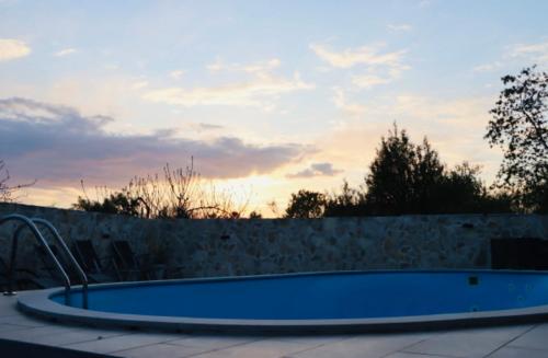 a blue swimming pool in a backyard with a wall at Iva apartman sa bazenom in Donji Zemunik