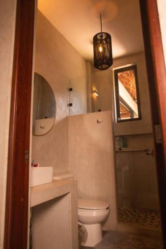a bathroom with a toilet and a sink and a mirror at Casa Mar Bacalar in Chetumal