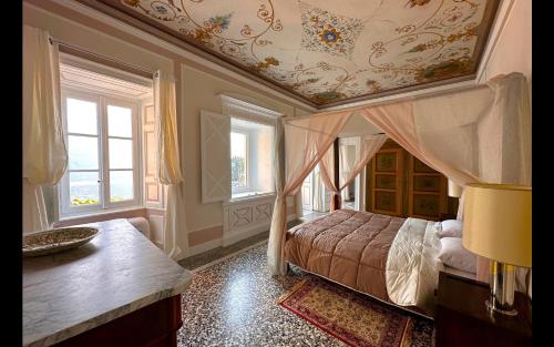 a bedroom with a canopy bed and windows at Cà del Conte Lake Como in Tremezzo