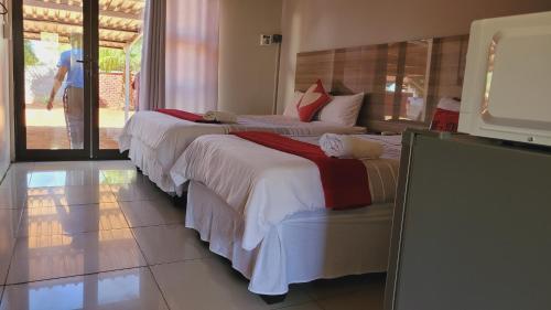 two beds in a room with a tv and a person walking at Pab-Love Guest House in Kuruman