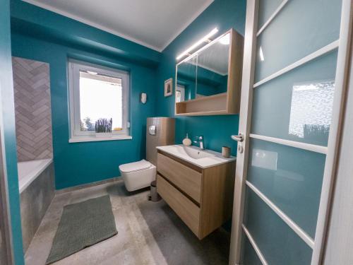 baño con paredes azules, lavabo y aseo en Vöröskő Apartmanház, en Balatonalmádi