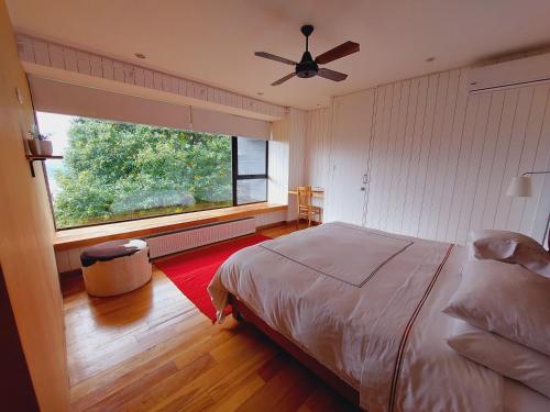 a bedroom with a bed and a large window at Hotel Casa Panguipulli in Panguipulli