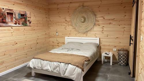 1 dormitorio con 1 cama en una pared de madera en אחוזת אבירי הגליל, en She'ar Yashuv