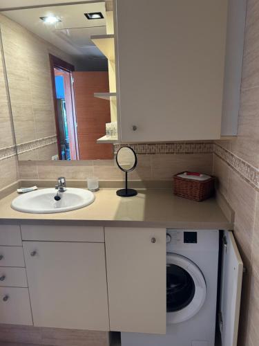 een badkamer met een wastafel en een wasmachine bij Apartamento Es Calo (Edificio Cavall de Llevant) in Es Calo