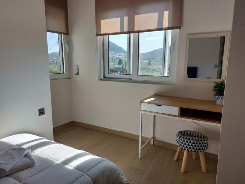 een slaapkamer met een bed, een bureau en ramen bij Endless View Apartment in Nafplio