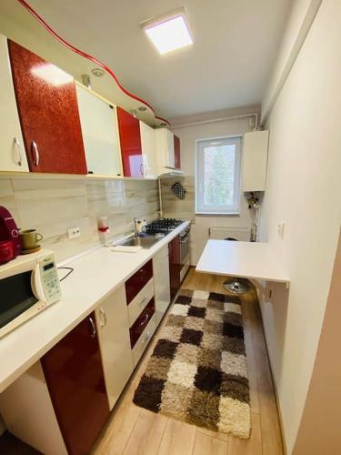 una cocina con encimeras blancas, fregadero y alfombra en A's apartment, en Onești