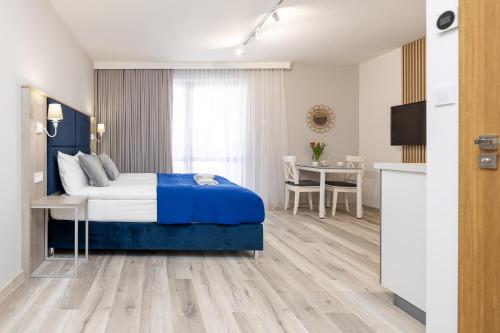 a bedroom with a bed and a table and a kitchen at Polanka Apartamenty in Niechorze