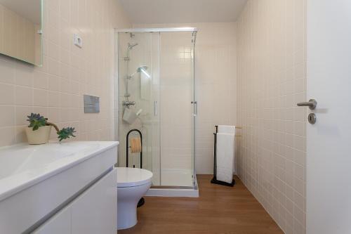 a white bathroom with a shower and a toilet at Casa Esmeralda by Home Sweet Home Aveiro in Aveiro
