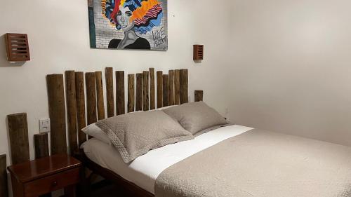 a bed with a wooden headboard in a bedroom at Aki Pousada in São Miguel do Gostoso