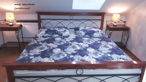 a bed with a blue comforter and pillows on it at Penzión Florens, Nesvady in Nesvady