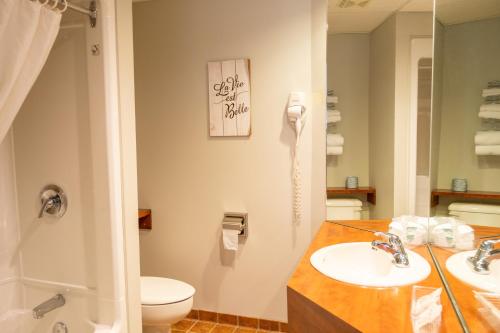 a bathroom with two sinks and a toilet and a shower at Hôtel Motel Le Voyageur in Saint-Georges