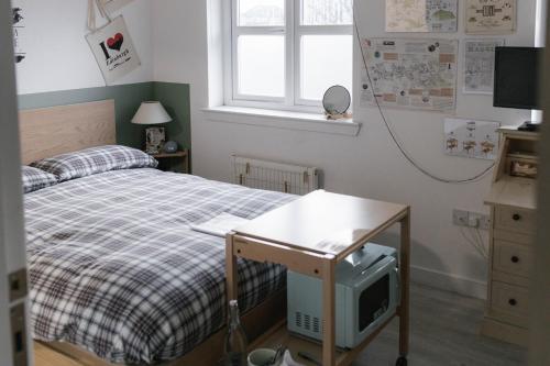 a bedroom with a bed and a desk with a tv at BroomHouse HomeStay in Edinburgh