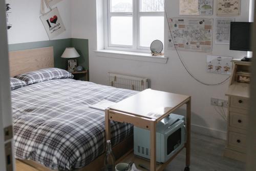 een slaapkamer met een bed en een bureau met een televisie bij BroomHouse HomeStay in Edinburgh