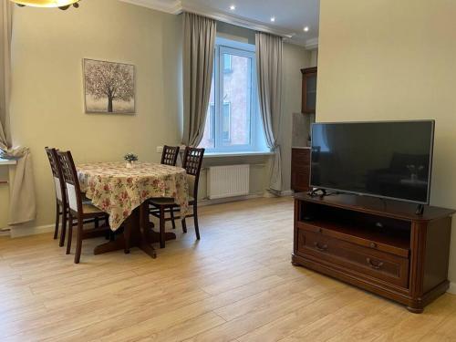 a dining room with a table with chairs and a television at Eksporta Street Quiet Old Riga Apartment in Rīga